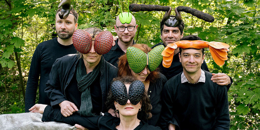 Gruppenbild Projekt Stumm Herum das Ende vom Lied, alle Künstler mit Insektenmasken in einer Grünfläche